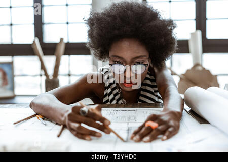 Pencil and ruler Dark-eyed young interior designer using pencil and ruler while painting sketches Stock Photo