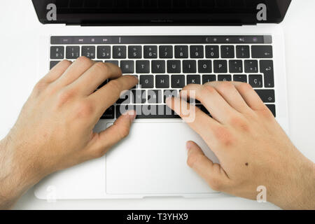 Business person using the keyboard and the touchpad of a laptop on a white table. Modern workplace. Stock Photo