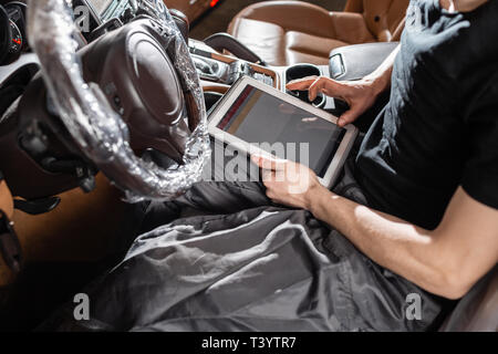 Computer diagnostics of electronic systems of the car. Car mechanic maintains a vehicle with the help of a diagnostic tablet computer. Modern Stock Photo
