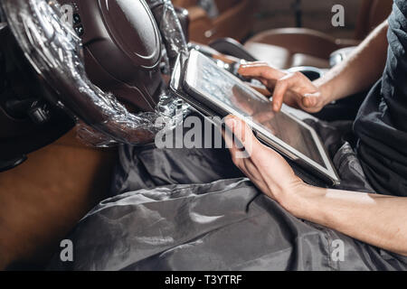 Computer diagnostics of electronic systems of the car. Car mechanic maintains a vehicle with the help of a diagnostic tablet computer. Modern Stock Photo