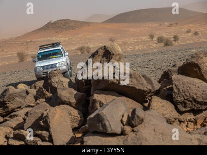 Meroe, Sudan, February 10., 2019: White off-road vehicle honter a collection of large stones in the gravel desert near Meroe, Sudan Stock Photo