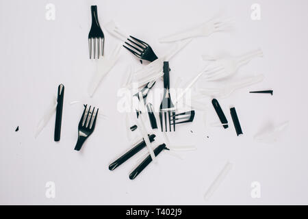 Plastic pollution concept. No to plastic. Scattered broken single-use white and black forks on dark background. New rules to reduce plastic waste, EU  Stock Photo