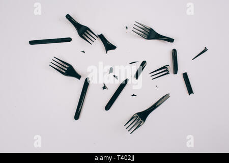Plastic pollution concept. Plastic free. Scattered broken single-use black forks on dark background, top view. New rules to reduce plastic waste, EU d Stock Photo