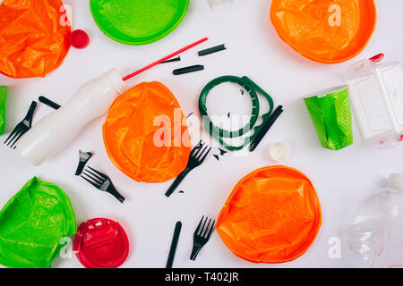 Be plastic free. Save ecology. Broken single-use colorful different plates, forks, cups, bottle, straw, lids on white background. New rules to reduce  Stock Photo