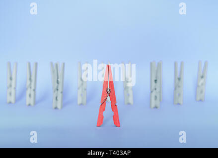 Unique, individuality, outstanding,leadership and think different concept. Red wooden clip stand out of colorless clips on blue backgrounds Stock Photo