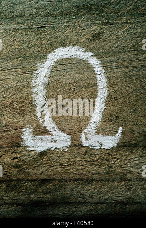 closeup of an omega letter painted with chalk on a rustic wooden surface Stock Photo