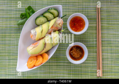 Vietnamese vegetarian spring rolls served with sauces. Wooden chopsticks on the side. Top view. Stock Photo