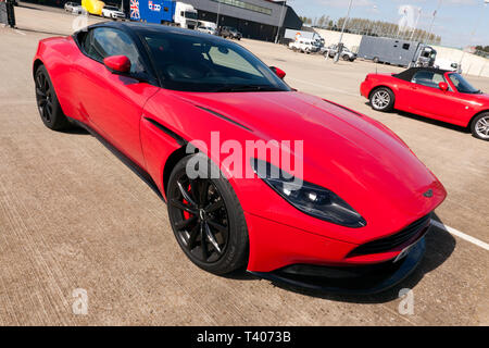 An red, Aston Martin DB11, parked in the International Paddock, during the 2019 Silverstone Classic Media Day Stock Photo