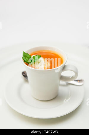 Gaspacho soup served in coffee cup with whipped cream and basil leaf Stock Photo