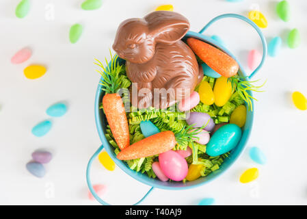 Easter basket filled with Easter grass, candy eggs, mini carrots, and a chocolate rabbit Stock Photo