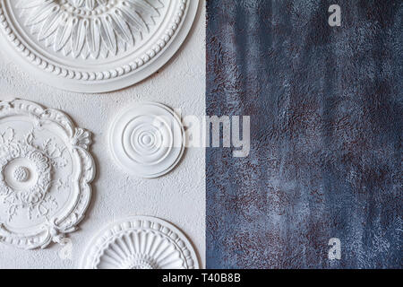 A two-color background, gray decorative plaster and a white wall with several white ceiling rosettes. Stock Photo