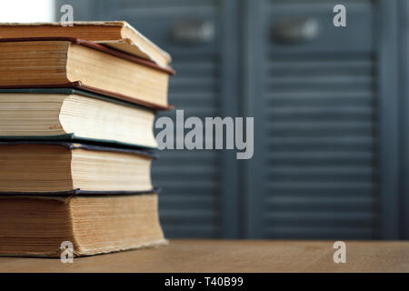 A stack of vintage books for business and education on a wooden surface against a white wall, back to school concept. Stock Photo