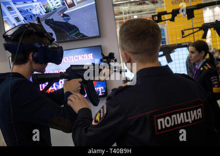 A police officer helps the visitor on the virtual reality simulator for police special forces at the stand of the Nizhny Novgorod Police Academy Stock Photo