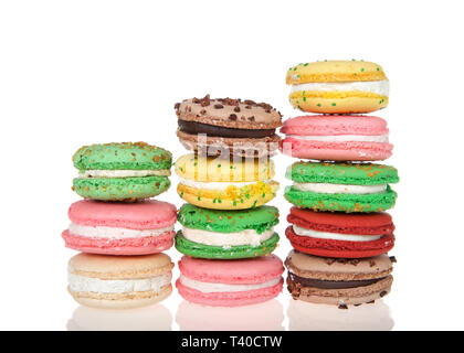 Three stacks varied heights of macaron cookies, multiple colors and flavors on a reflective surface isolated on white. Traditional french treat. Stock Photo
