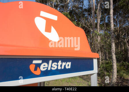 The distinctive orange top of a traditional Telstra public phone booth on a footpath in a rural village now almost redundant due to mobile phones Stock Photo