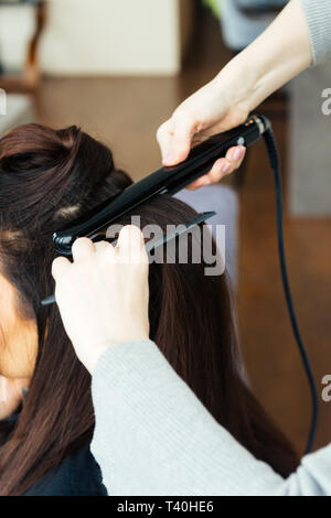 Hairdresser straightening models hair in a beauty salon Stock Photo