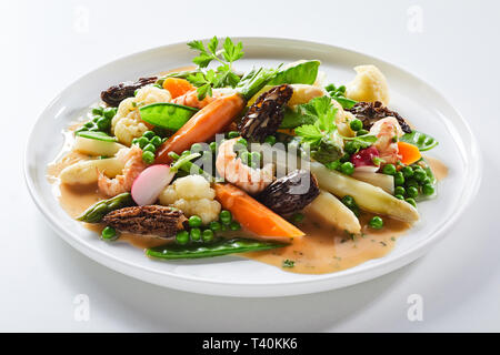 Gourmet hot salad with morel mushrooms and fresh white asparagus spears served with mangetout peas, carrots, cauliflower and fresh coriander Stock Photo