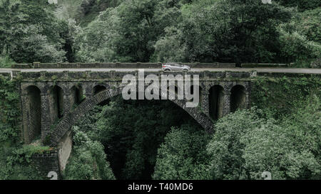 Drone aerial view of a tone bridge crosses a stream in Cruzinhas, Faial, Madeira island Stock Photo