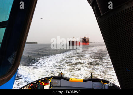 Port operations managing and transporting iron ore. From leading tug to transhipper or TSV in shipping channel to meet OGV ocean going ship  at sea Stock Photo