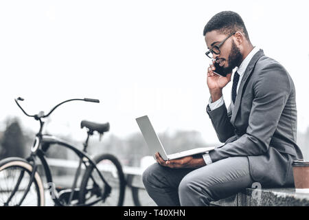 Always in touch. Businessman with bicycle working on laptop Stock Photo