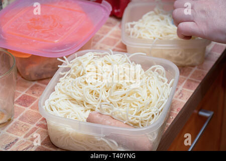 Noodles with sausage in lunch box on kitchen table. Noodles in plastic container Stock Photo