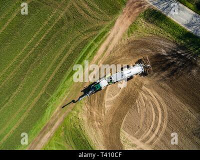 aerial view of a tractor with a modern ground fertilizer trailer on agricultural field Stock Photo