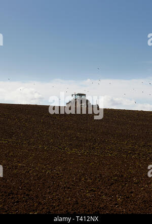 A tractor cultivating a field on a hill Stock Photo