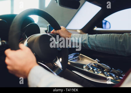 Businessman driving luxury modern car in the city. Close up man's hand on the wheel of the car. Stock Photo