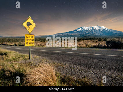 Kiwi crossing sign at night next to snowy Mount Ruapehu in New Zealand's Tongariro national park. Stock Photo