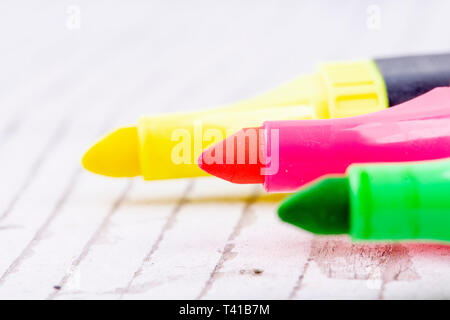 three colorful highlighters on white rustic wood Stock Photo