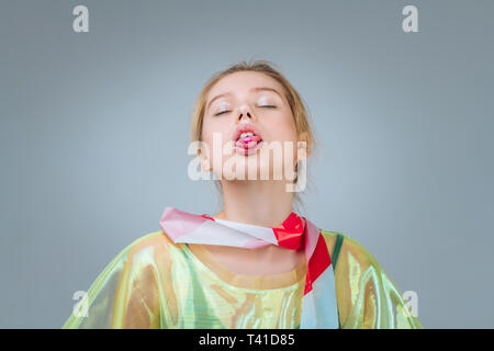 Extravagant model. Young extravagant blonde-haired model posing near grey background showing nice poses Stock Photo