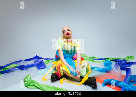 Surrounded by plastic. Professional model sitting on the floor surrounded by colorful non-natural plastic Stock Photo