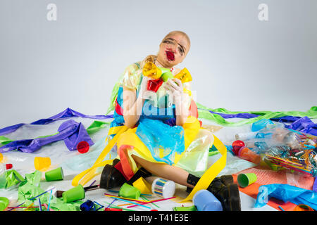 Plastic trash. Model wearing plastic clothes sitting on floor surrounded by plastic trash posing for ecology campaign Stock Photo