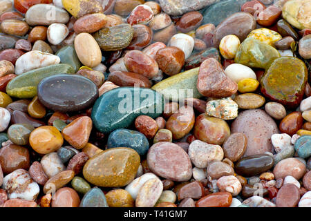Pebbles left wet and colourful on the beach as the tide goes out. Stock Photo