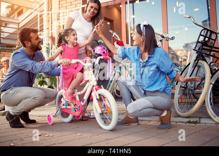 Selling bicycle - Young family buy new bicycle for happy little girl in bike shop Stock Photo