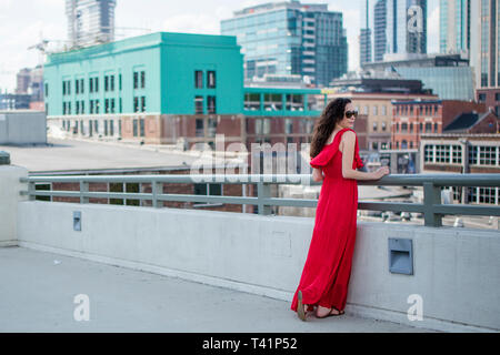 a windblown woman in a red dress smiles against a city backdrop Stock ...