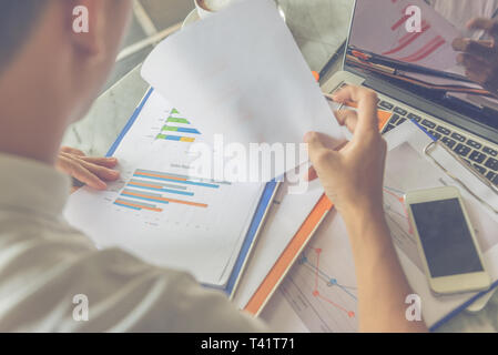 Rear view of Asian office employee checking financial documents Stock Photo
