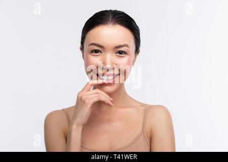 Dark-eyed woman. Dark-eyed appealing young woman wearing beige camisole smiling broadly Stock Photo