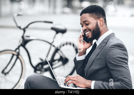 African-american businessman using laptop, having break outdoors