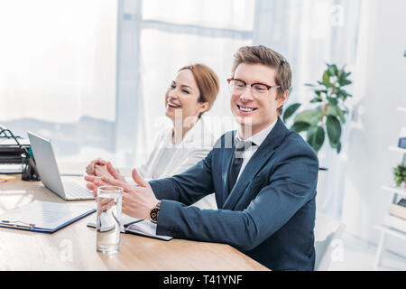 handsome recruiter in glasses smiling near attractive coworker Stock Photo