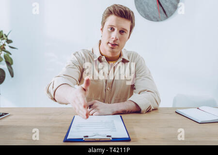selective focus of handsome recruiter gesturing near clipboard Stock Photo