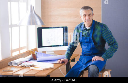 Engineer carpenter working on laptop and sketching project. Stock Photo