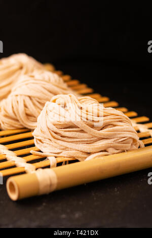 Asian Food concept homemade uncook oriental egg noodles on bamboo tray with copy space Stock Photo
