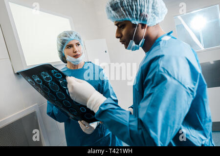 good-looking and beautiful doctors in uniforms and medical masks talking about x-ray Stock Photo