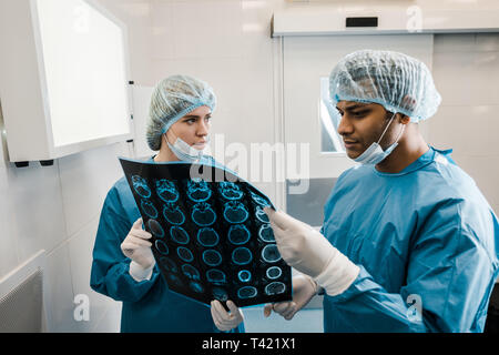handsome and beautiful doctors in uniforms and medical masks talking about x-ray Stock Photo
