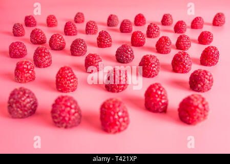 Pattern made from fresh raspberries, view from the skew, isolated on a light pink background. Stock Photo