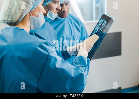 handsome and attractive doctors in uniforms and medical masks talking about x-ray Stock Photo
