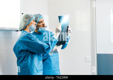 handsome and beautiful doctors in uniforms holding x-ray and talking Stock Photo