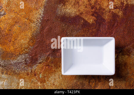 Empty white cornered bowl on rusted metal background, top view Stock Photo