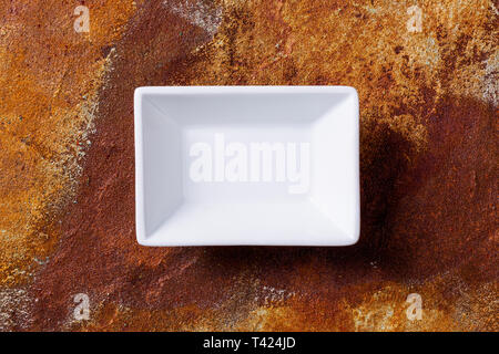Empty white cornered bowl on rusted metal background, top view Stock Photo